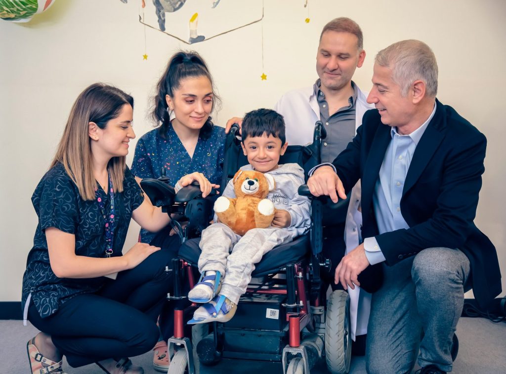a group of people standing around a baby in a wheel chair